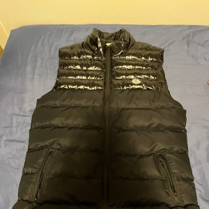Svart Moncler Väst  - Har aldrig använt den. Bra skick 10/10. Passar perfekt för sommaren