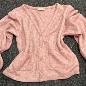Rosa kofta från Nelly i stickad bomull - Supermjuk rosa kofta från Nelly i stickad bomullsmix. Koftan har v-ringning, knappar framtill och två stora fickor. Perfekt för lager-på-lager och chill dagar. Långärmad och loose fit för en avslappnad vibe. Använd endast 1 gånger och tvättad bara en gång. Köpt för 500 kr. Priset kan diskuteras 😊