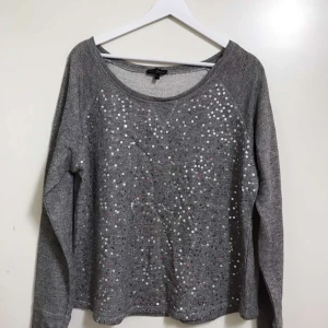 Grå paljetttröja - Grå långärmad tröja från KappAhl med glittrande paljetter framtill. 