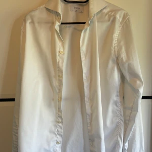 Vit skjorta från Eton i bomull - Klassisk vit skjorta från Eton med lång ärm och knappar framtill. Skjortan har en stilren design med krage och är tillverkad i mjuk bomull. Perfekt för dig som gillar en clean och tidlös look.