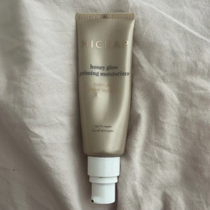 Hickap Honey Glow Priming Moisturizer - Honey Glow Priming Moisturizer från Hickap är en vegansk primer i en lyxig guldig tub med pump. Den ger glow och återfuktar huden, perfekt som bas innan smink. Passar alla hudtyper och innehåller ingredienser som ger lyster och mjuk känsla.