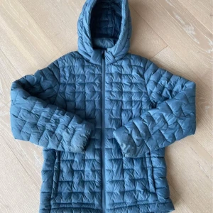 Blå dunjacka från Everest med huva - Säljer en blå dunjacka från Everest i storlek 158/164. Jackan har quiltad design, huva och dragkedja framtill. Perfekt för kyliga dagar och enkel att matcha med olika outfits. Snygg och funktionell jacka för dig som vill hålla värmen. Använd fåtal gånger. Motagare står för frakten.