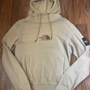 The North Face Hoodie - Beige hoodie från The North Face. Perfekt för dig som gillar streetwear och vill ha en stilren look. Använd 10-tal gånger och är i mycket bra skick!