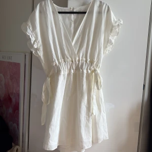 Klänning från Zara - Vit klänning från Zara. Man kan knyta den i midjan och den har ett stretchigt band i ryggen! Säljer då den e lite kort för min smak