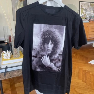 Svart Limitato t-shirt med fotoprint - Svart t-shirt från Limitato med ett stort, svartvitt fotoprint framtill. Tillverkad i 100% merceriserad bomull för en lyxig känsla. Klassisk passform med rund hals och korta ärmar. Grym statement-piece för dig som gillar unik design.