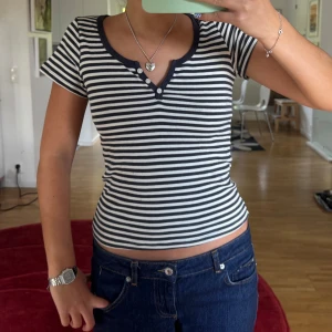 Randig kortärmad topp med knappar - Randig T-shirt med knappar. Från Brandy Melville 