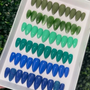 Färgglada lösnaglar i grönt och blått - Säljer ett set med lösnaglar i olika nyanser av grönt och blått, både matta och glittriga. Naglarna är mandelformade och kommer med tillbehör som nagelfil, träpinne, lim och klisterflikar. Perfekt för att fixa snygga naglar hemma med coola färgkombinationer.
