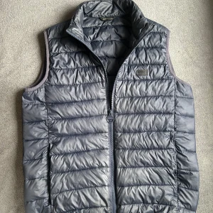 Mörkblå dunväst från Barbour - Snygg mörkblå dunväst från Barbour med quiltad design och hög krage. Perfekt nu inför hösten! Cond: 9/10 inga defekter förutom smått vanligt slitage. Storlek S. Hör av er vid frågor! Mvh