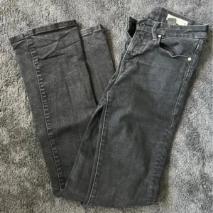 Svarta bootcut jeans - Säljer ett par grå Levis 501 jeans med klassisk femficksdesign och bootcut-ben. Jeansen har en rak passform och är tillverkade i slitstarkt bomullsjeans. Perfekta för dig som gillar en tidlös och avslappnad stil.