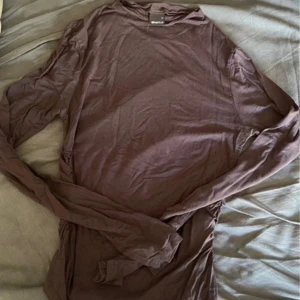 Grå långärmad tröja  - En basic brun långärmad tröja från Weekday i mjuk bomull. Perfekt att ha som lager eller bara till ett par jeans. Enkel och stilren design med rund halsringning och normal passform.