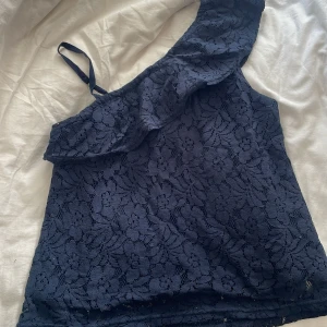 Marinblå spetsig oneshoulder-top Abercrombie - Supersnygg marinblå topp från Abercrombie Kids med blommig spets och oneshoulder-design. Helt ny aldrig använt.