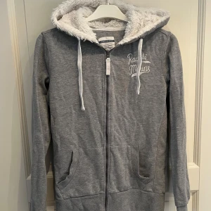 Grå hoodie Race med päls luva - Mysig cool grå hoodie från Race Marine med vit päls huva och vita snören🥰🥰 Tröjan har dragkedja, två fickor fram och tryck på bröstet. 