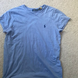 Ljusblå t-shirt från Polo Ralph Lauren - Snygg ljusblå t-shirt från Polo Ralph Lauren i mjuk bomull. Klassisk passform med korta ärmar och rund halsringning. Klassiska hästen på bröstet.Tröjan är köpt ifrån zalando för 1000 kr, knappast använd.