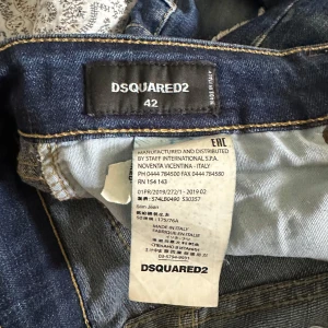 Dsquared2 slim jeans med slitningar - Snygga blå slim jeans från Dsquared2 med slitna detaljer och coola hål framtill. Jeansen har klassisk femficksdesign, knappar med logga och en röd Dsquared2-patch bak. Tillverkade i Italien i mjukt bomullstyg med stretch.