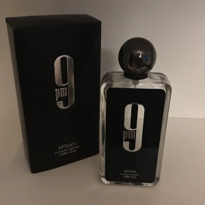 Afnan 9pm Eau de Parfum 100ml - Afnan 9pm är en parfym i en stilren, rektangulär glasflaska med svart etikett och stor, rund svart kork. Flaskan rymmer 100 ml och kommer i en elegant svart kartong med silverdetaljer. Doften är en eau de parfum och passar dig som gillar moderna och snygga flaskor. Det är ungefär 85-90 ml kvar. 