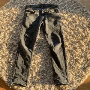 Grå Lee Daren jeans W31 L30 - Säljer ett par grå Lee Daren Zip Fly jeans i klassisk rak modell. Jeansen har fem fickor, dragkedjegylf och snyggt tvättad finish. Perfekta för dig som gillar en stilren look med lite edge. Materialet är mjukt och följsamt denim.
