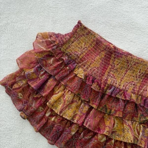 Mäster kjol från Zara  - Supersöt kort volangkjol med paisleyinspirerat mönster i gult, rött och inslag av lila. Kjolen har flera lager volanger och smock i midjan för en bekväm passform. Tunt, flowy material . Dock har kjolen skador då lite sömmar har släppt och Darför säljer jag billigare . 