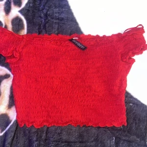 Röd croppad topp från H&M Divided - Superfin röd croppad topp med smockad struktur och offshoulder-modell. Toppen har vågig kant nertill och är perfekt för dig som vill sticka ut med en färgstark look. Snygg att matcha med höga jeans eller kjol.