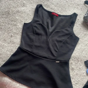 Svart linnetopp från Guess - Snygg svart linnetopp från Guess med v-ringad skärning och figurnära passform. 