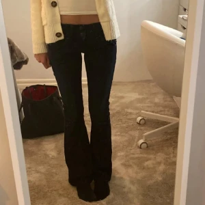 Mörkblå bootcut jeans från LTB - Snygga mörkblå jeans från LTB med bootcut passform och låg midja. Jeansen har dubbla knappar i midjan, klassiska fem fickor och coola detaljer på bakfickan. Tillverkade i stretchigt denim därför passar dom även personer med storlek 26/27. Har sytt om dom till bootcut