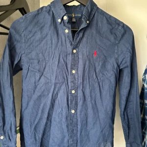 Ralph lauren skjorta - Fet raffe skjorta i mörkblå färg. Storlek 10-12y men passar om du är runt 160! Bra skick och priset är förhandlingsbart!