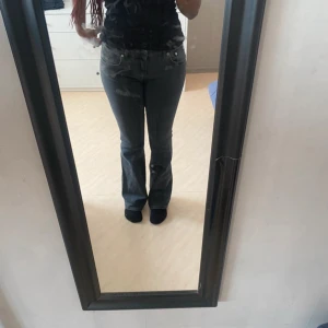 Mörkgrå bootcut jeans - Snygga mörkgrå jeans med bootcut passform och klassisk femficksdesign. Jeansen har en midwaist och är tillverkade i ett stretchigt denimtyg som sitter skönt på kroppen. Perfekta för dig som gillar en tidlös look med lite utsvängda ben.
