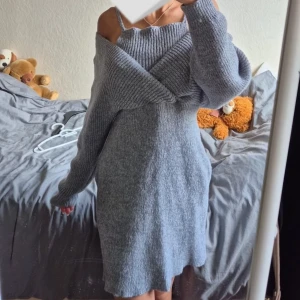 Grå stickad offshoulder klänning - Supermysig grå stickad kortklänning med offshoulder och långa ärmar. Den har en bred ribbad kant upptill som ger en snygg och avslappnad look. Perfekt för dig som vill vara både bekväm och trendig. Säljs pågrund av för stor. 