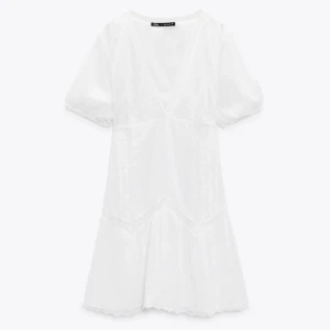 Vit kort klänning från Zara XS - Supersöt vit kort klänning från Zara i luftig bomull med v-ringning, puffärmar och fina spetsdetaljer. Perfekt för varma dagar och ger en fräsch och romantisk vibe. Klänningen har en lätt volang nertill och markerad midja.