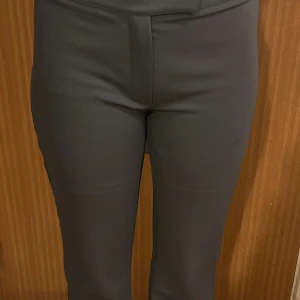 Mörk Gråa  vida kostymbyxor - Snygga svarta kostymbyxor med hög midja och vida ben. Byxorna har en stilren look och är tillverkade i ett mjukt, vävt material som ger en dressad känsla. Perfekta att styla med crop top eller oversized skjorta för en trendig vibe.