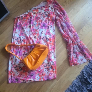 Blommig meshklänning från Bodyflirt - Superfin blommig meshklänning från Bodyflirt med en ärm och offshoulder-design. Klänningen har färger i rosa, rött, lila och vitt, samt transparent lång ärm. Perfekt för dig som vill sticka ut med en färgglad och trendig look. Du får väskan på köpet !!!