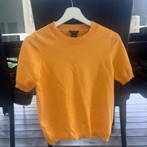 Orange kortärmad tröja från Lindex - Snygg orange tröja från Lindex i storlek XS. Tröjan har korta ärmar, rund halsringning och är tillverkad i mjuk bomull. Perfekt för dig som vill ha en färgklick i garderoben och gillar enkel, stilren design.