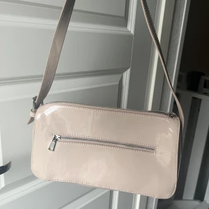 Beige lack väska från H&M - Säljer denna söta väska från H&M. Den har mycket bra skick men några små repor finns som man kan se i första bilden.