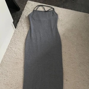 Grå långklänning med smala axelband från Shein - Säljer en stilren grå långklänning med smala axelband och figurnära passform, Skims inspirerad, från Shein. Klänningen har minimalistisk design och är perfekt för dig som gillar enkel men snygg stil. Passar lika bra till sneakers som till klackar.