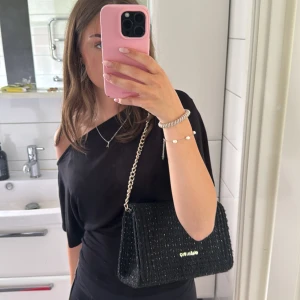 Svart axelväska från Valentino - Säljer en svart axelväska från Valentino som är lite glittrig och med ett band som går att justera. Använd fåtal gånger och säljer då den inte kommer till användning. Köpt för 1200, kvitto finns! Kan gå ner i pris