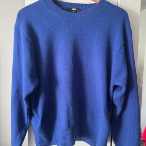 Blå stickad tröja från Uniqlo - En klassisk blå stickad tröja från Uniqlo med rund halsringning och ribbade muddar. Tröjan har en relaxed passform och är perfekt för lager-på-lager. Enkel och stilren design som funkar till allt.