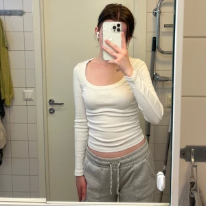 Långärmad vit topp från Gina Tricot - Säljer en vit långärmad topp med rund, djup ringning.     Materialet är ribbat och stretchigt. Storlek XS men passar även S. Knappt använd då det är fel storlek för mig. Köptes för 199kr. Finns även i ljusrosa, båda tröjorna för 110kr eller en för 70kr!