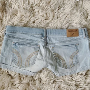 HOLLISTER Ljusblåa lågmidjade shorts - Sååå snygga! Midja rakt över: ca 41 cm💞 Men den har två knappar vilket kan ses på sista bilden så går att göra den mindre också! (Jag har den yttre knappen på bilderna)💞 Finns även två pyttesmå fläckar som knappt märks men får ej plats i annonsen så skriv för bild på de💞