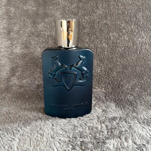Parfums de Marly Layton EdP 125ml - Lyxig parfym från Parfums de Marly, Layton EdP 125ml. Flaskan är matt mörkblå med silverdetaljer och har två upphöjda hästar och sköld på framsidan. Kommer med originalkartong i svart med silverränder och logga. Perfekt för dig som gillar exklusiva dofter.