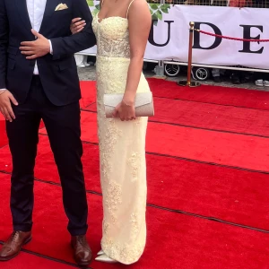 Ljusgul långklänning med spetsdetaljer - Superfin ljusgul långklänning med tunna axelband Perfekt för bal eller student! Sitter figurnära och ger en elegant siluett.