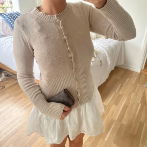 Beige kofta med knappar och ribbade detaljer🍨🤍 - Supersöt beige kofta med långa ärmar och ribbade muddar. Koftan har en snygg, figurnära passform och knappar framtill med en liten volangkant längs knappraden. Perfekt att slänga över en klänning eller till jeans🍨🤍