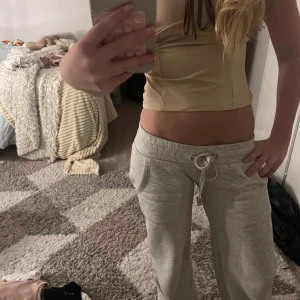 Beige linne med bruna detaljer - Supersnygg beige linne-topp med tunna axelband och bruna kanter. Toppen har en söt knytning framtill och är croppad i modellen. Perfekt för varma dagar eller att styla lager på lager. Materialet känns mjukt och stretchigt.