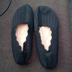 Svarta stickade ballerinaskor - Snygga svarta ballerinaskor med stickad ovandel och vågig kant runt öppningen. Skorna har en platt ljus sula och diskret mönsterstickning som ger en cool touch. Perfekta för dig som gillar enkel men trendig stil.