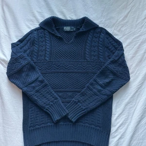 Mörkblå stickad tröja Polo Ralph Lauren - Snygg mörkblå stickad tröja från Polo Ralph Lauren i 100% bomull. Tröjan har ett grovt stickat mönster, krage och långa ärmar. Liten ”defekt” där knapparna är lite fladdriga vid kragen. Skriv för frågor! Flexibelt pris. 