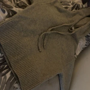 Grå stickad hoodie från Zara - Mysig grå stickad hoodie från Zara i storlek L. Tröjan har huva med snörning, långa ärmar och bred ribbad mudd nedtill. Sitter som en M