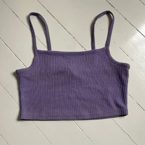 Lila ribbad linnetopp - Säljer en lila ribbad linnetopp med smala axelband och rak halsringning. Toppen är croppad och har en enkel, stilren design som passar perfekt till sommaren. Blir billigare vid köp av flera. Skriv för flera bilder💜