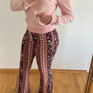 Mönstrade utsvängda byxor - Säljer ett par färgglada utsvängda byxor . Byxorna har hög midja och är i stretchigt material som sitter tight upptill och blir vida nertill. 