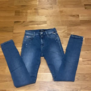 Blå replay jeans med slitningar -  👖✨ Kolla in dessa snygga blå jeans från Replay! ✨👖 Med sin klassiska design är de ett måste i garderoben. De har en praktisk dragkedja och knapp framtill, vilket gör dem lätta att ta på och av. 👌 De diskreta slitningarna ger en trendig och avslappnad look som passar perfekt för alla tillfällen.  Kombinera dem med din favorittopp och sneakers för en chill vardagsstil. 👟👕 Dessa jeans i storlek 150 är redo att rocka!