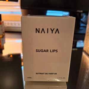 NAIYA Sugar Lips Extrait de Parfum 50ml inspirerad av Prada Paradox - Säljer en exklusiv parfym från NAIYA med namnet Sugar Lips. Flaskan rymmer 50 ml och är designad i en stilren, vit förpackning med minimalistisk text. Perfekt för dig som gillar unika dofter och snygg design.