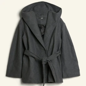 Mörkgrå kappa med huva och bälte - INTRESSEKOLL på en mörkgrå kappa med stor huva och knytskärp i midjan. Kappan har en rak passform utan knytningen i midjan.  Perfekt för kyliga dagar under vår och höst🩶knappt använd, mycket bra skick