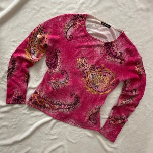 Rosa paisleymönstrad topp från Just Woman - Säljer en rosa långärmad topp från Just Woman med färgstarkt paisleymönster i gult, svart och lila. Tunn och stretchig med rund halsringning. Några pärlor sitter lite löst (sista bilden)
